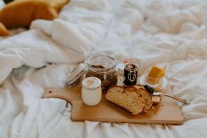 ein Tablett mit Essen, einem Sandwich, Marmelade und einem Glas Milch in der Unterkunft Parcel Tiny House I Le P'tit Clos Normand 