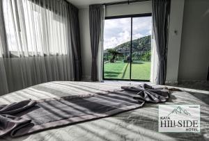 Ce lit se trouve dans une chambre dotée d'une grande fenêtre. dans l'établissement Kata Hillside Hotel, à Kata Beach