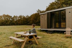 una mujer sentada en una mesa de picnic frente a una cabaña en Parcel Tiny House I Elevage du Puits Carré, en Dame-Marie 13 fotos más
