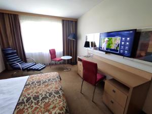 a hotel room with a bedroom with a tv on a desk at Hotel HP Park Poznań Malta Sport in Poznań