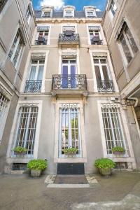 un bâtiment avec des fenêtres et des plantes en pot devant lui dans l'établissement Le Saint Michel, à Dijon