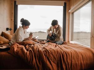 Dos personas sentadas en una cama en un dormitorio en Parcel Tiny House I Chèvrerie de Rilly en Cravant