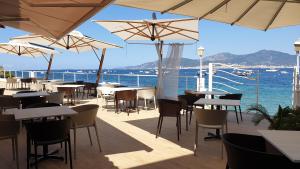 a restaurant with tables and umbrellas and the ocean at Hôtel U Paradisu in Porticcio