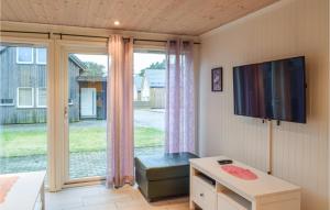 a living room with a tv and a large window at Beautiful Home In Sgne With House A Panoramic View in Søgne