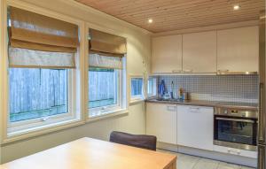 a kitchen with a wooden table and two windows at Stunning Home In Søgne in Søgne
