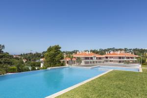 a large swimming pool in front of a house at Estoril Queens Apartment by CadenzaLux in Estoril