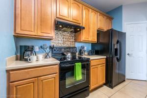 a kitchen with wooden cabinets and a stove and refrigerator at Stunning Top-Floor Condo, next to Clubhouse in Orlando