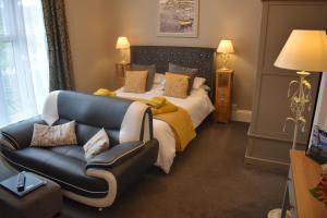 a bedroom with a bed and a leather couch at Acorn Lodge in Torquay