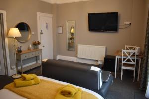 a bedroom with a bed and a television on the wall at Acorn Lodge in Torquay