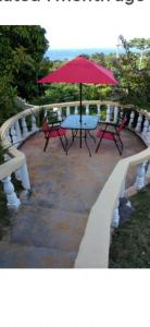 una mesa de picnic con una sombrilla roja en el patio en Royal Villa 360 en Port Antonio