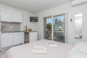 a white bedroom with a bed and a kitchen at Apartments M&A in Makarska