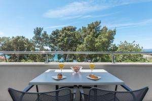 a table and chairs on a balcony with two glasses of wine at Apartments M&A in Makarska