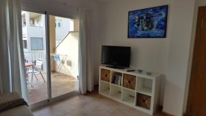 a living room with a television and a balcony at Espalmador 19 in Es Pujols