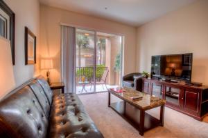 a living room with a leather couch and a television at Cozy Condo w FREE Vista Cay Resort Access in Orlando