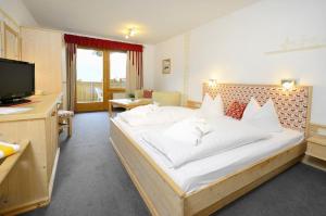 1 dormitorio con 1 cama grande y TV en Hotel Pfleger en Anras