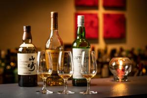 three wine bottles and three wine glasses on a counter at Villa Sanjomuromachi KYOTO in Kyoto