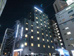 名古屋的住宿－HOTEL LiVEMAX Nagoya Kanayama，一座高大的建筑,晚上在城市里装有窗户