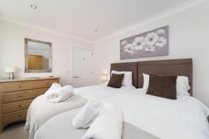 a bedroom with two beds and a dresser and a mirror at The Barn in St Ives