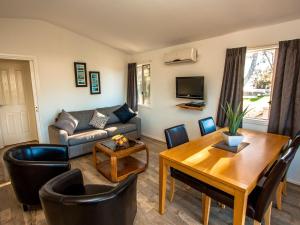 uma sala de estar com um sofá e uma mesa em Caseys Beach Holiday Park em Sunshine Bay