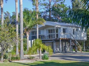 a house with palm trees in front of it at Caseys Beach Holiday Park in Sunshine Bay