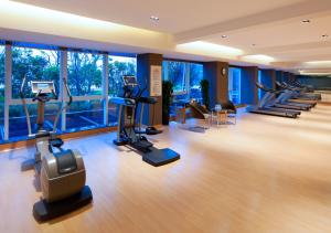 un gimnasio con cintas de correr, máquinas elípticas y ventanas en Wingtech Hotel, en Huangshi