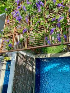 un balcón con flores púrpuras junto a una piscina en Ikiru 18 Private Saltwater Pool Villa, 3 Ensuite BR, Outdoor BBQ, 5 mins to Beach, en Pantai Cenang