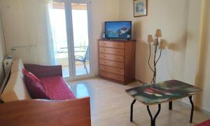 a living room with a couch and a tv on a dresser at Hellmann Apartments in Afionas