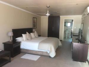a bedroom with a large white bed and a bathroom at The Lazy Grape Guest Lodge & Spa in Benoni