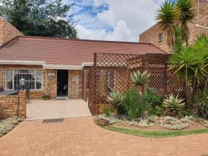 a brick house with a courtyard and palm trees at The Lazy Grape Guest Lodge & Spa in Benoni