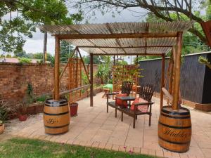a patio with a wooden pergola and a table and chairs at The Lazy Grape Guest Lodge & Spa in Benoni