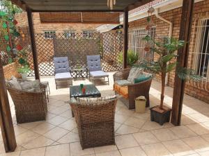 a patio with wicker chairs and a table and chairs at The Lazy Grape Guest Lodge & Spa in Benoni