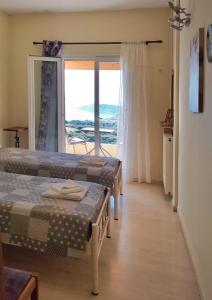 a room with two beds and a large window at Hellmann Apartments in Afionas