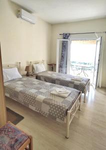 two beds in a room with a large window at Hellmann Apartments in Afionas