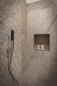 a shower with a hose in a bathroom with a wall at Al Duomo B&B in Amantea