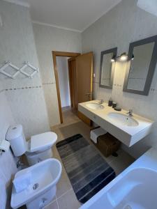 a bathroom with two sinks and a toilet and a mirror at Apartamentos Santa Teresinha in Alvor