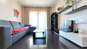 uma sala de estar com um sofá e uma televisão em Apartamentos Turisticos Rocha Tower 4 em Portimão