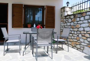 a table and chairs on a patio with a stone wall at Kassiani House in Theológos