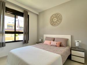 1 dormitorio con 1 cama blanca y 2 almohadas rosas en Higuericas 411 - Planta baja - vista piscina - cerca playa, en Pilar de la Horadada