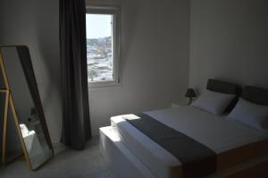 a bedroom with a bed and a mirror and a window at Revel Mykonos 4 in Mýkonos City