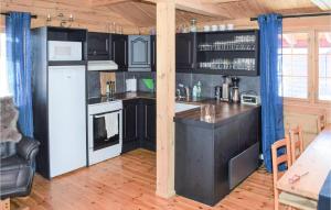 Nice Home In Hovden I Setesdal With 5 Bedrooms, Sauna And Wifi في هوفدين: مطبخ فيه دواليب سوداء وثلاجة بيضاء