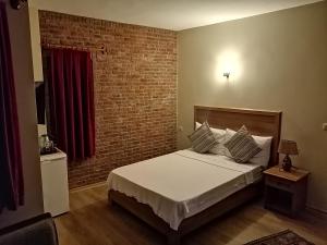 a bedroom with a bed and a brick wall at Casa Callinos in Selcuk