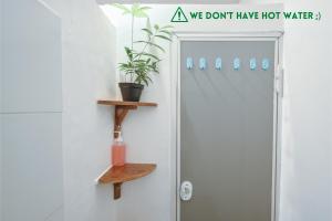 a bathroom with a shower door with a sign that says we dont have hot water at Snooze in Yogyakarta