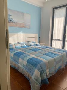 een slaapkamer met een bed met een blauwe en witte deken bij A casa di Nonna Maria in Marcelli