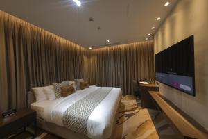 een slaapkamer met een bed en een flatscreen-tv bij The Hotel Andrea in Cauayan