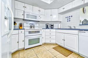 una cucina bianca con armadietti e elettrodomestici bianchi di Beach Palms 406 a Clearwater Beach