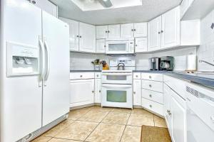 una cocina blanca con armarios y electrodomésticos blancos en Beach Palms 406, en Clearwater Beach