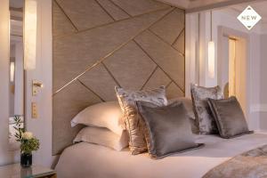 a bed with white pillows and pillows on it at Hotel du Collectionneur Arc de Triomphe in Paris
