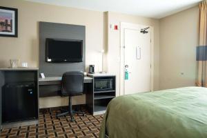 a hotel room with a desk with a computer and a bed at Quality Inn Raynham - Taunton in Raynham