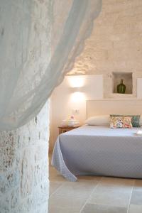 a bedroom with a bed and a stone wall at Dimore Angiulli - Trulli di Charme in Castellana Grotte