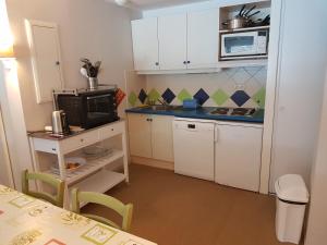 una pequeña cocina con armarios blancos y microondas en Grand T3 - Terrasse les pieds dans l'eau - Climatisation, en Saint-Raphaël